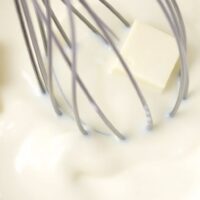 A bowl with milk and butter being whisked together.