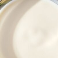Bowl of milk with butter and flour ingredients around it.